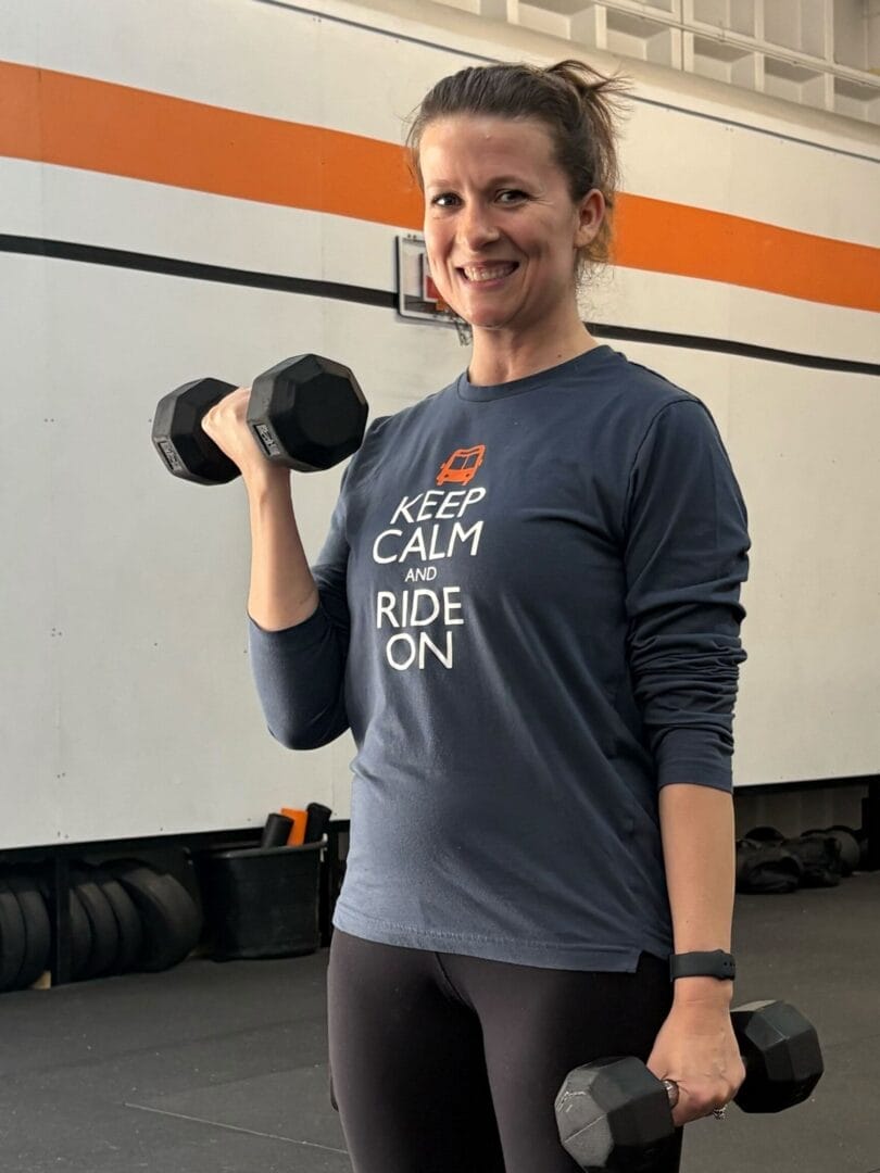 NHF client smiling while holding dumbbells during strength training session